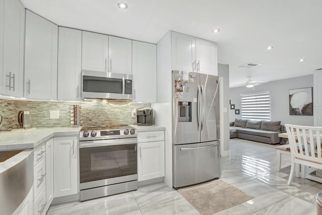 kitchen featuring appliances with stainless steel finishes, ceiling fan, decorative backsplash, and white cabinets