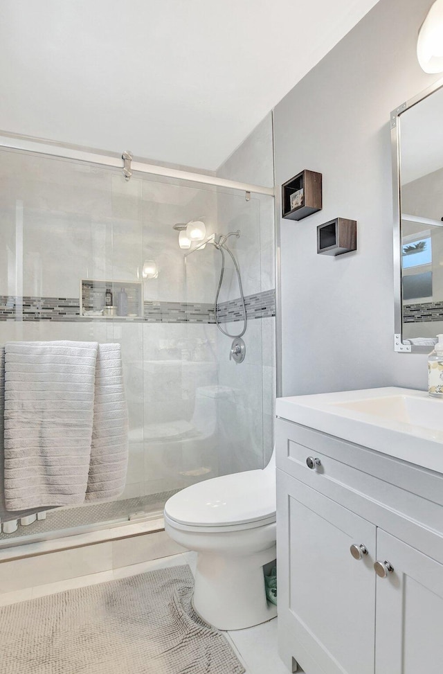 bathroom featuring vanity, tile patterned flooring, toilet, and walk in shower