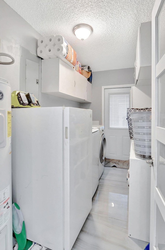 laundry area with washing machine and dryer, water heater, cabinets, and a textured ceiling