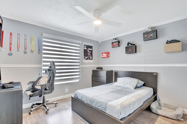 bedroom with wood-type flooring, ornamental molding, a textured ceiling, and ceiling fan