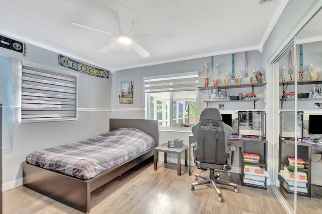 bedroom featuring ornamental molding, hardwood / wood-style flooring, ceiling fan, and a textured ceiling