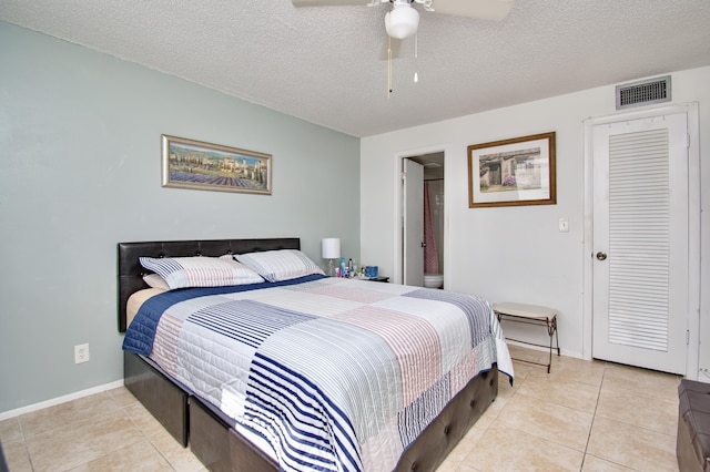 bedroom featuring light tile patterned floors, baseboards, visible vents, and a textured ceiling