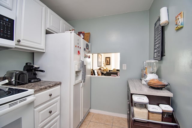 kitchen with dark countertops, white appliances, white cabinetry, and light tile patterned floors