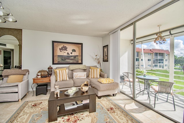 living room with a textured ceiling, light tile patterned flooring, visible vents, and floor to ceiling windows