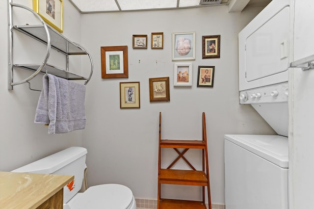 bathroom featuring vanity, toilet, and stacked washer / drying machine