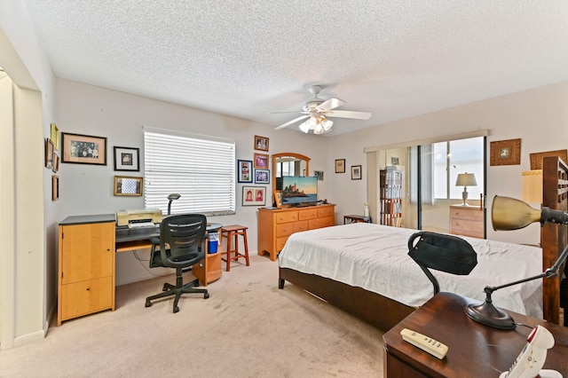 bedroom with ceiling fan, light carpet, and a textured ceiling