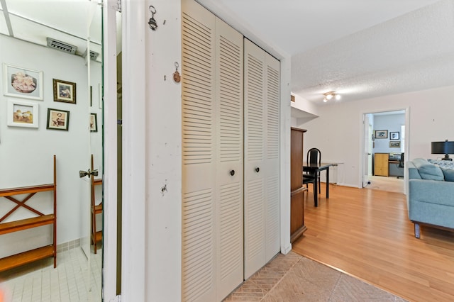 corridor with light wood-type flooring and a textured ceiling