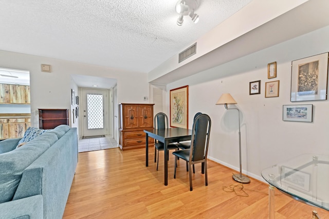 dining room with a textured ceiling and light wood-type flooring