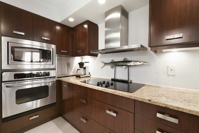 kitchen with wall chimney exhaust hood, decorative backsplash, light stone countertops, and appliances with stainless steel finishes