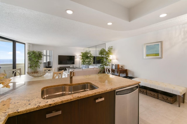 kitchen featuring light stone countertops, a water view, stainless steel dishwasher, and sink