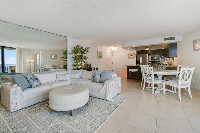 living room featuring light tile patterned floors, a textured ceiling, and ceiling fan