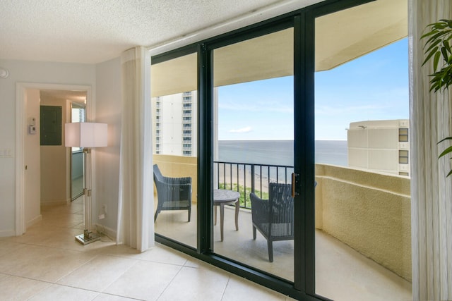 interior space with a textured ceiling, electric panel, a water view, and light tile patterned flooring