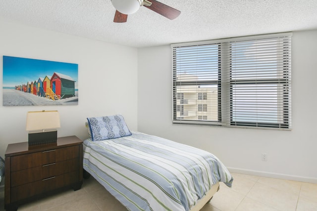 tiled bedroom with multiple windows, a textured ceiling, and ceiling fan