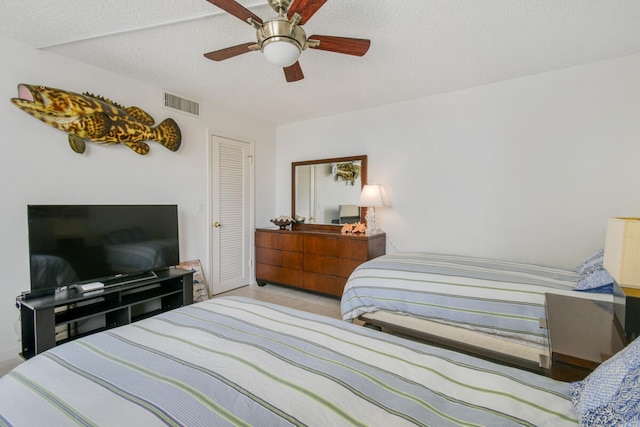 bedroom with ceiling fan, a closet, and a textured ceiling