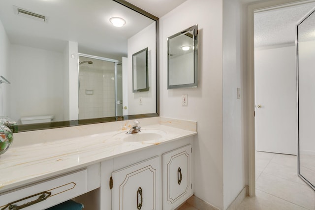 bathroom featuring tile patterned flooring, vanity, toilet, and an enclosed shower