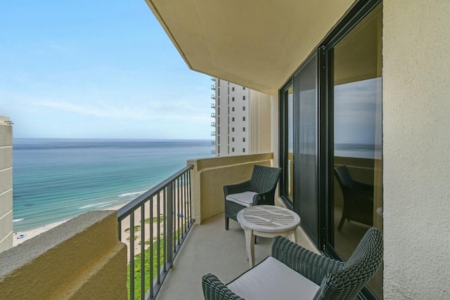 balcony with a water view and a view of the beach