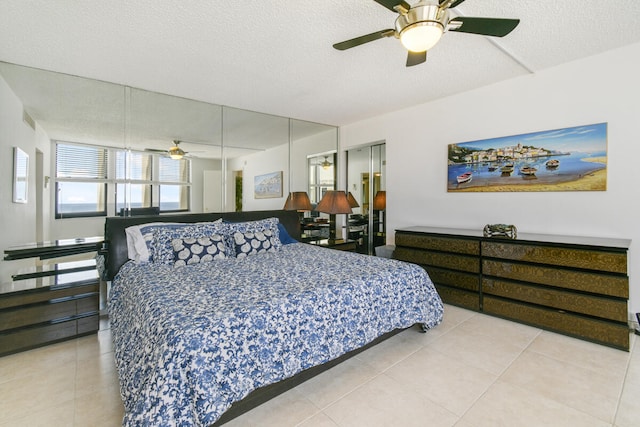 bedroom with ceiling fan, tile patterned flooring, and a textured ceiling