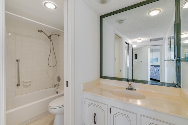 full bathroom with vanity, a textured ceiling, toilet, and tiled shower / bath