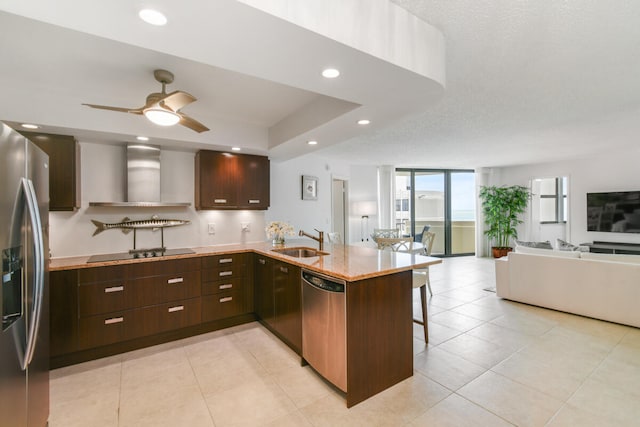 kitchen featuring sink, wall chimney range hood, kitchen peninsula, a breakfast bar, and appliances with stainless steel finishes