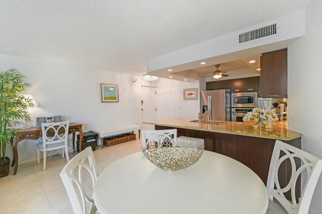 tiled dining space with a textured ceiling and ceiling fan