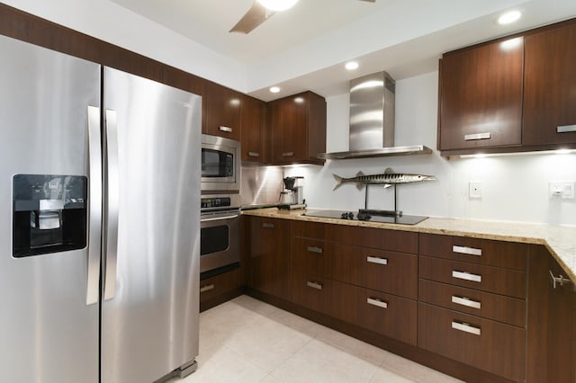 kitchen featuring stainless steel appliances, wall chimney range hood, tasteful backsplash, light stone counters, and light tile patterned flooring