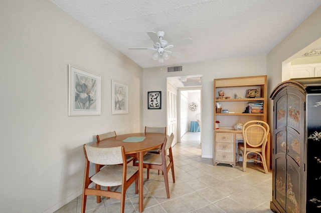 tiled dining room featuring a textured ceiling and ceiling fan