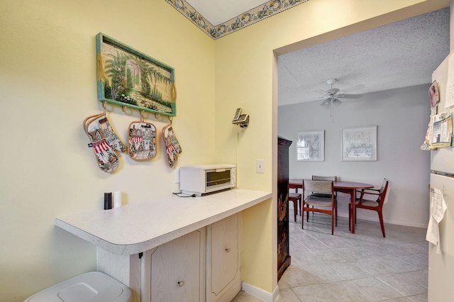 kitchen featuring a textured ceiling, light tile patterned floors, and ceiling fan