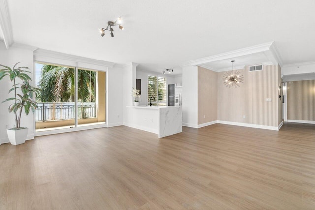 unfurnished living room with wood-type flooring, a wealth of natural light, crown molding, and sink