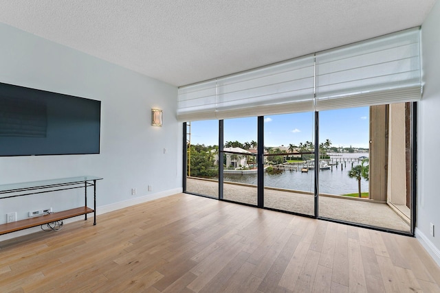 unfurnished living room featuring plenty of natural light, a water view, and light hardwood / wood-style floors