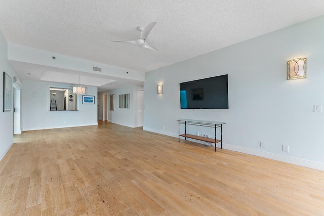 unfurnished living room with a textured ceiling, ceiling fan with notable chandelier, and light wood-type flooring