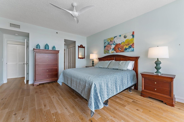 bedroom with light wood-type flooring, a textured ceiling, and ceiling fan