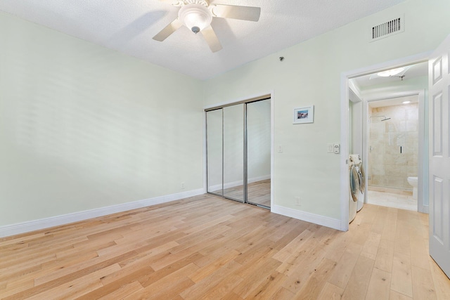 unfurnished bedroom with light hardwood / wood-style floors, a closet, separate washer and dryer, ceiling fan, and a textured ceiling