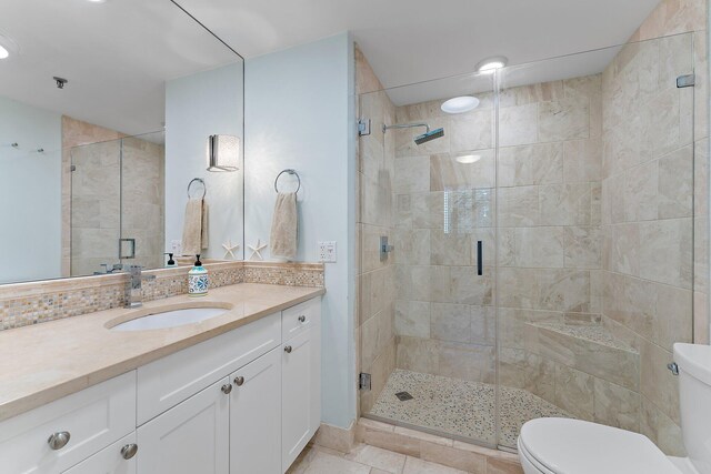 bathroom with a shower with door, vanity, toilet, and tile patterned flooring