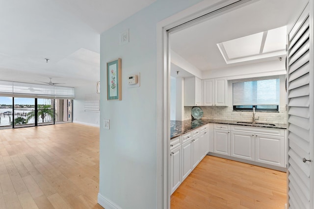 kitchen featuring light hardwood / wood-style flooring, ceiling fan, white cabinetry, and sink