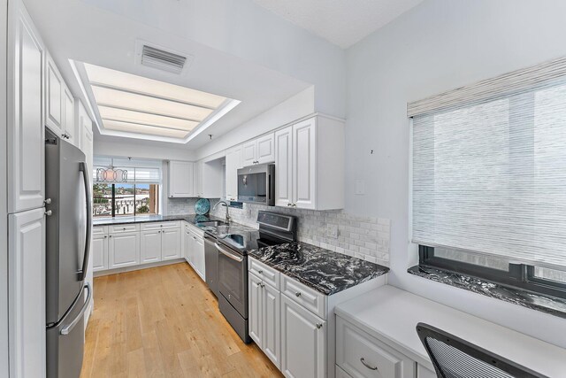 kitchen with appliances with stainless steel finishes, sink, decorative backsplash, white cabinetry, and light wood-type flooring