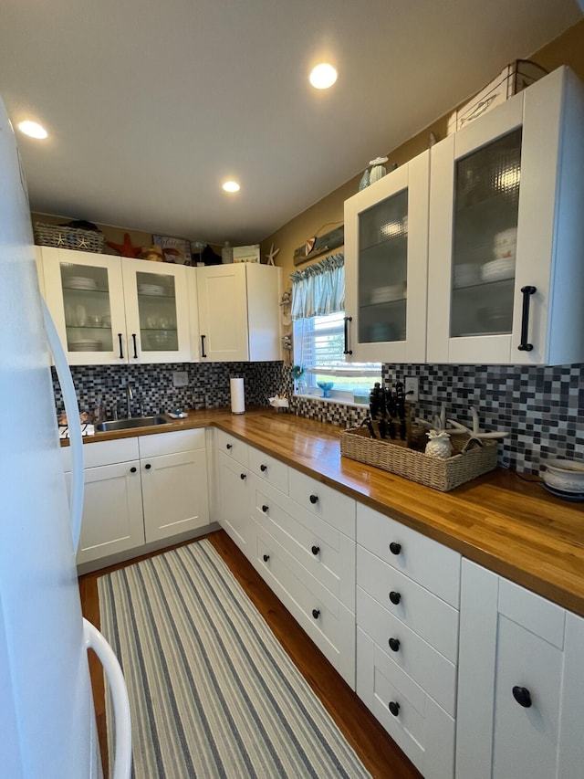 kitchen featuring dark hardwood / wood-style floors, butcher block countertops, tasteful backsplash, sink, and white cabinets