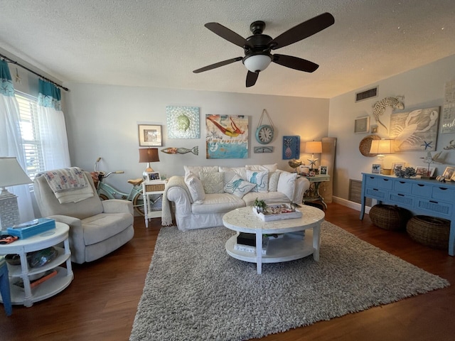 living room with dark wood-type flooring, ceiling fan, and a textured ceiling