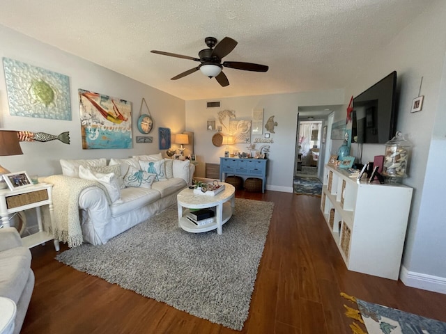 living room with dark wood-type flooring, ceiling fan, and a textured ceiling