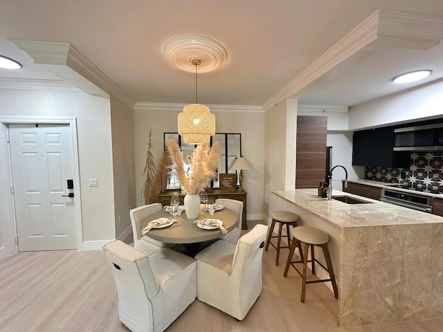 dining area featuring sink, crown molding, and light hardwood / wood-style flooring