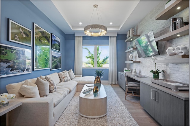 living room featuring a raised ceiling and light wood-type flooring