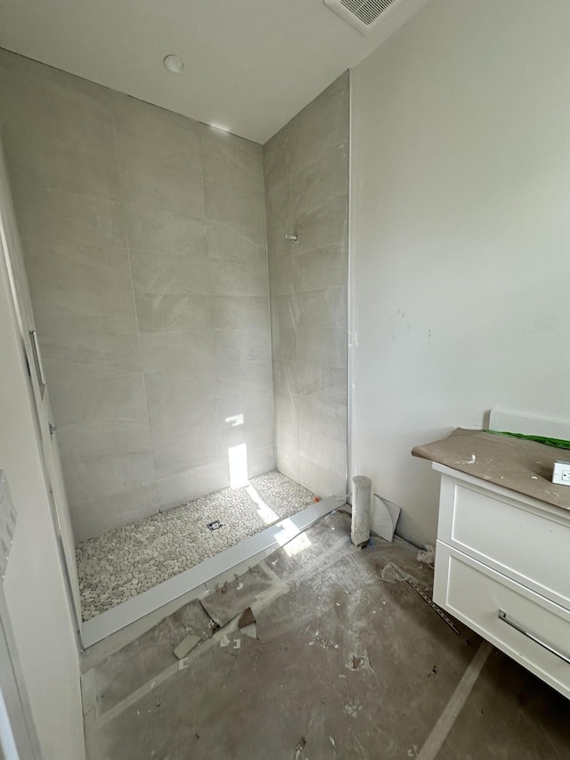 bathroom with vanity and a tile shower