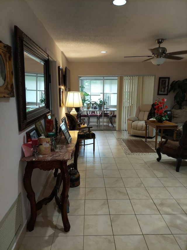 living room featuring light tile patterned flooring, ceiling fan, and a textured ceiling