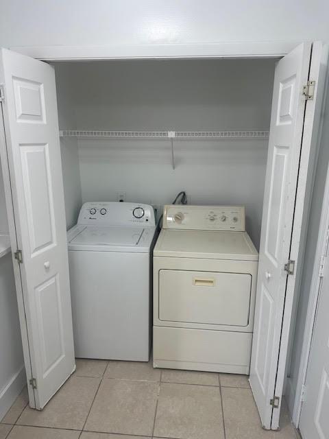 laundry area with independent washer and dryer and light tile patterned flooring