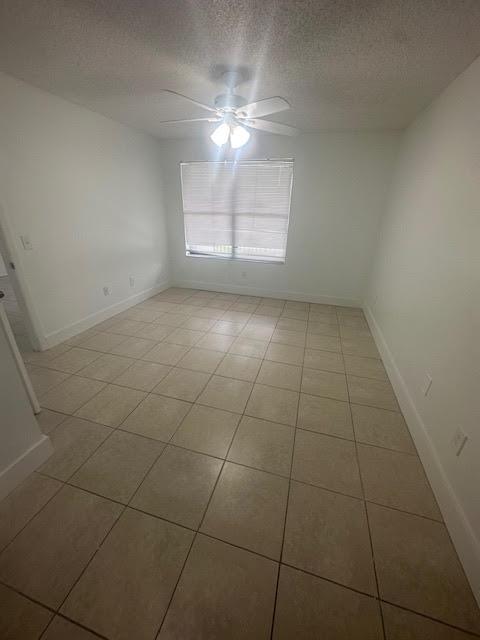 tiled spare room featuring a textured ceiling and ceiling fan