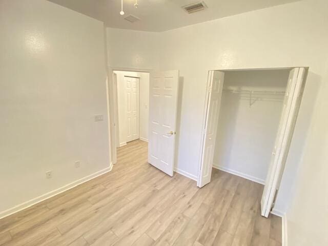 unfurnished bedroom featuring light hardwood / wood-style flooring and a closet