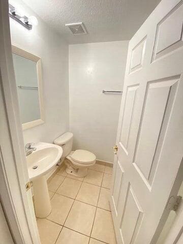 bathroom featuring toilet, tile patterned flooring, and a textured ceiling