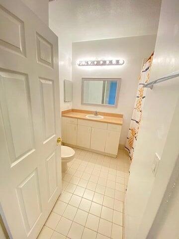 bathroom with tile patterned flooring, toilet, walk in shower, and vanity