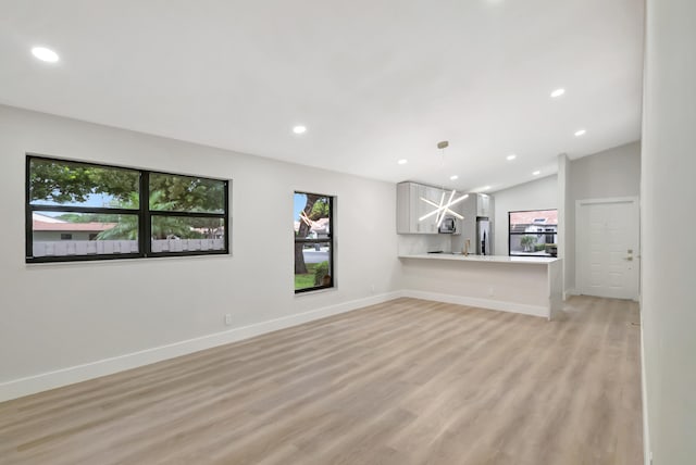 unfurnished living room featuring light wood-type flooring and lofted ceiling