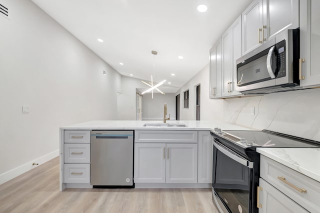 kitchen featuring kitchen peninsula, sink, stainless steel appliances, and light hardwood / wood-style flooring