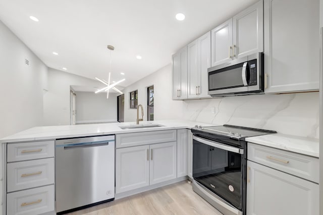 kitchen with light hardwood / wood-style floors, tasteful backsplash, sink, light stone countertops, and appliances with stainless steel finishes